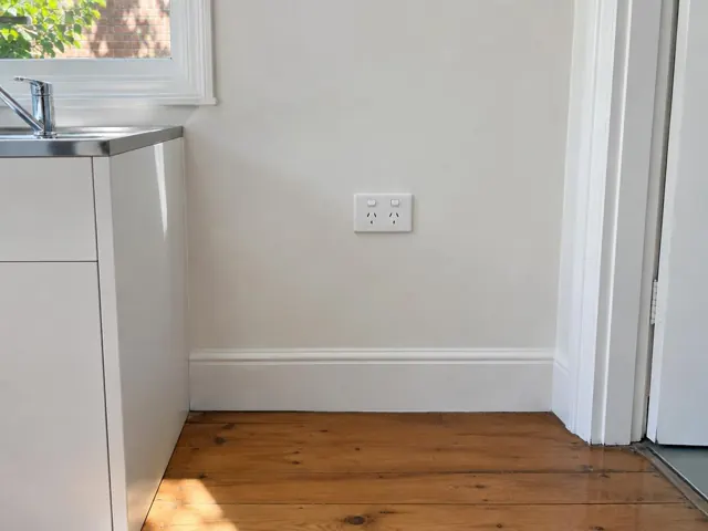 Double power point on a painted kitchen wall above timber floorboards in a home in Newtown